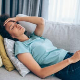 Woman lying on couch with body aches