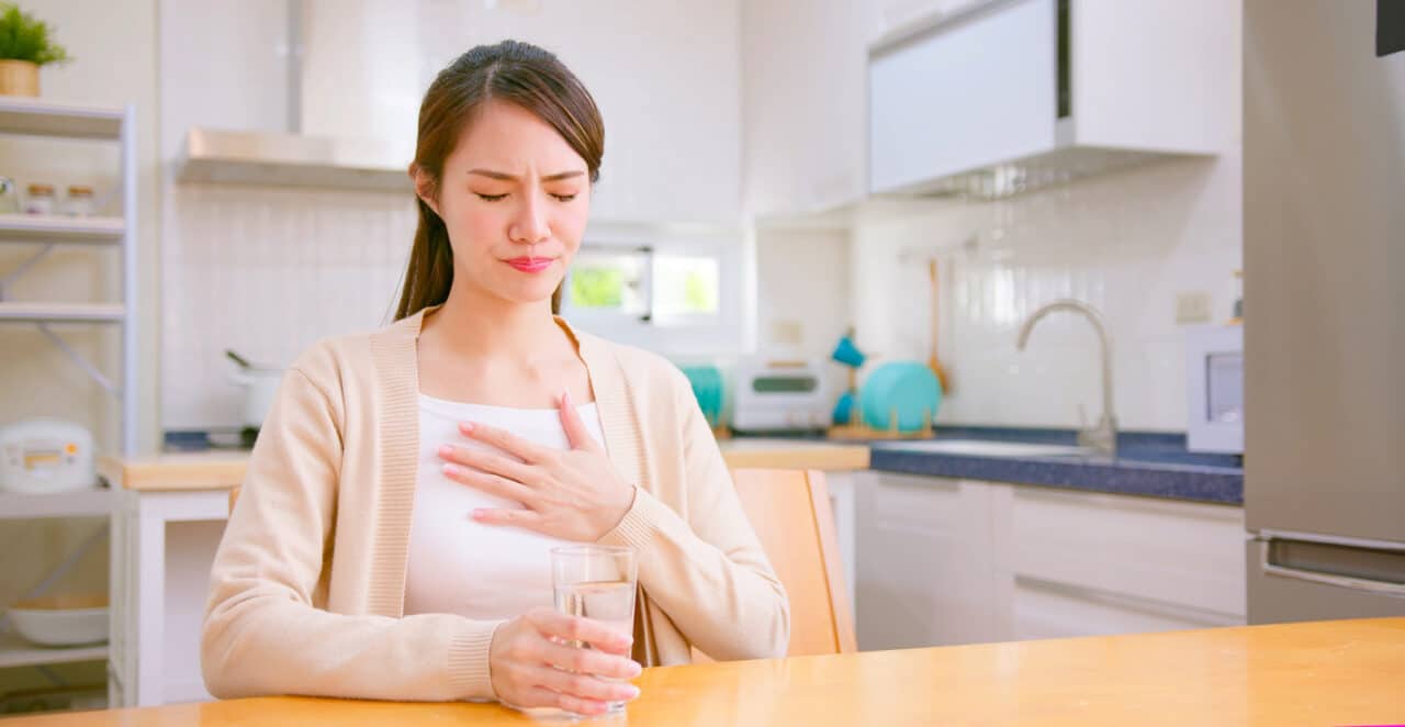 Woman with acid reflux placing her hand on her chest.