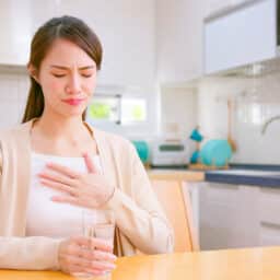 Woman with acid reflux placing her hand on her chest.