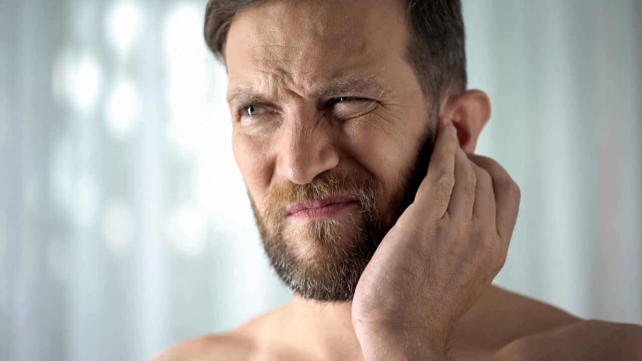 Man with ear pain holds ear
