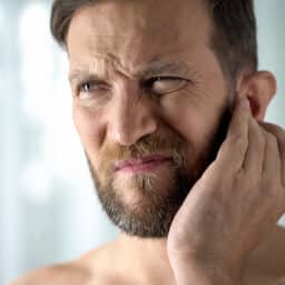 Man with ear pain holds ear