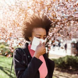 Woman sneezes near trees
