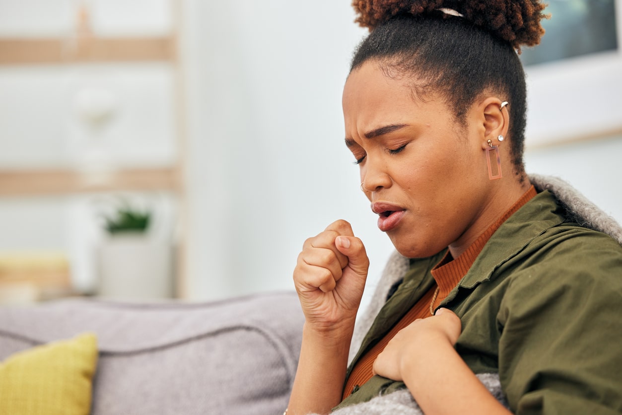 Woman coughing and holding her chest.