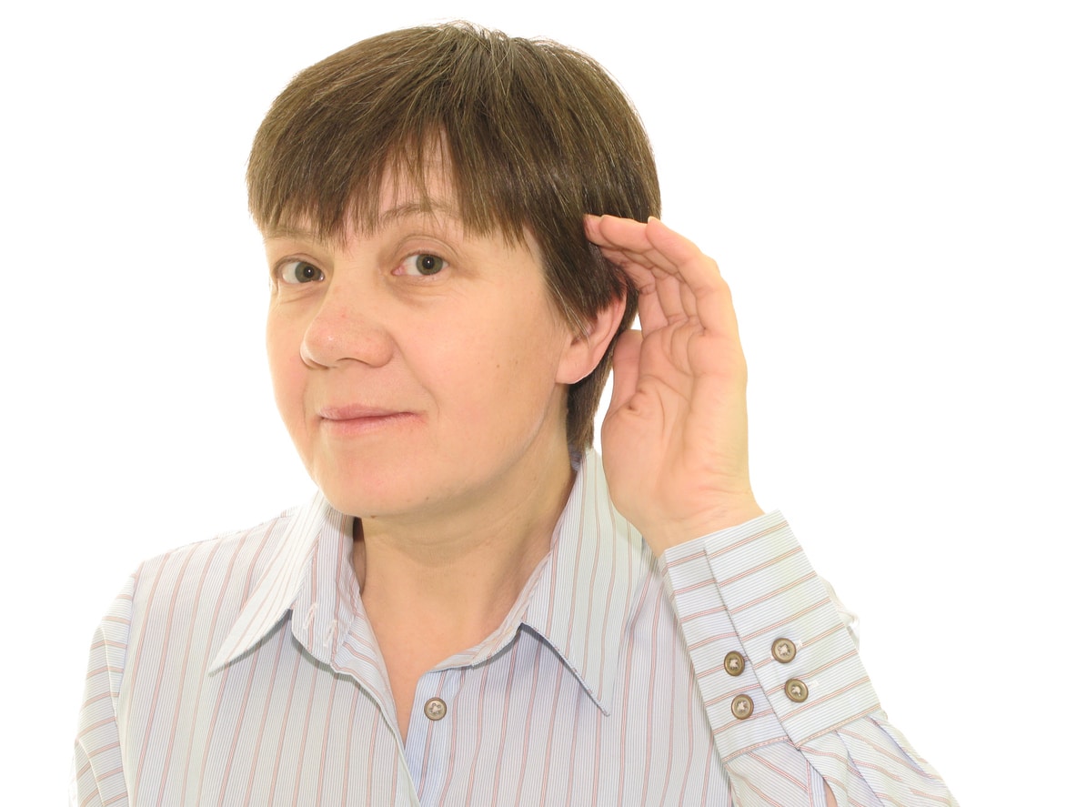 Woman with her hand to her ear straining to understand.