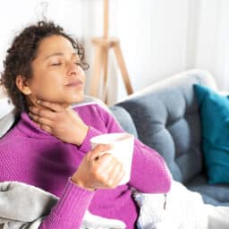 Woman holds neck with sore throat