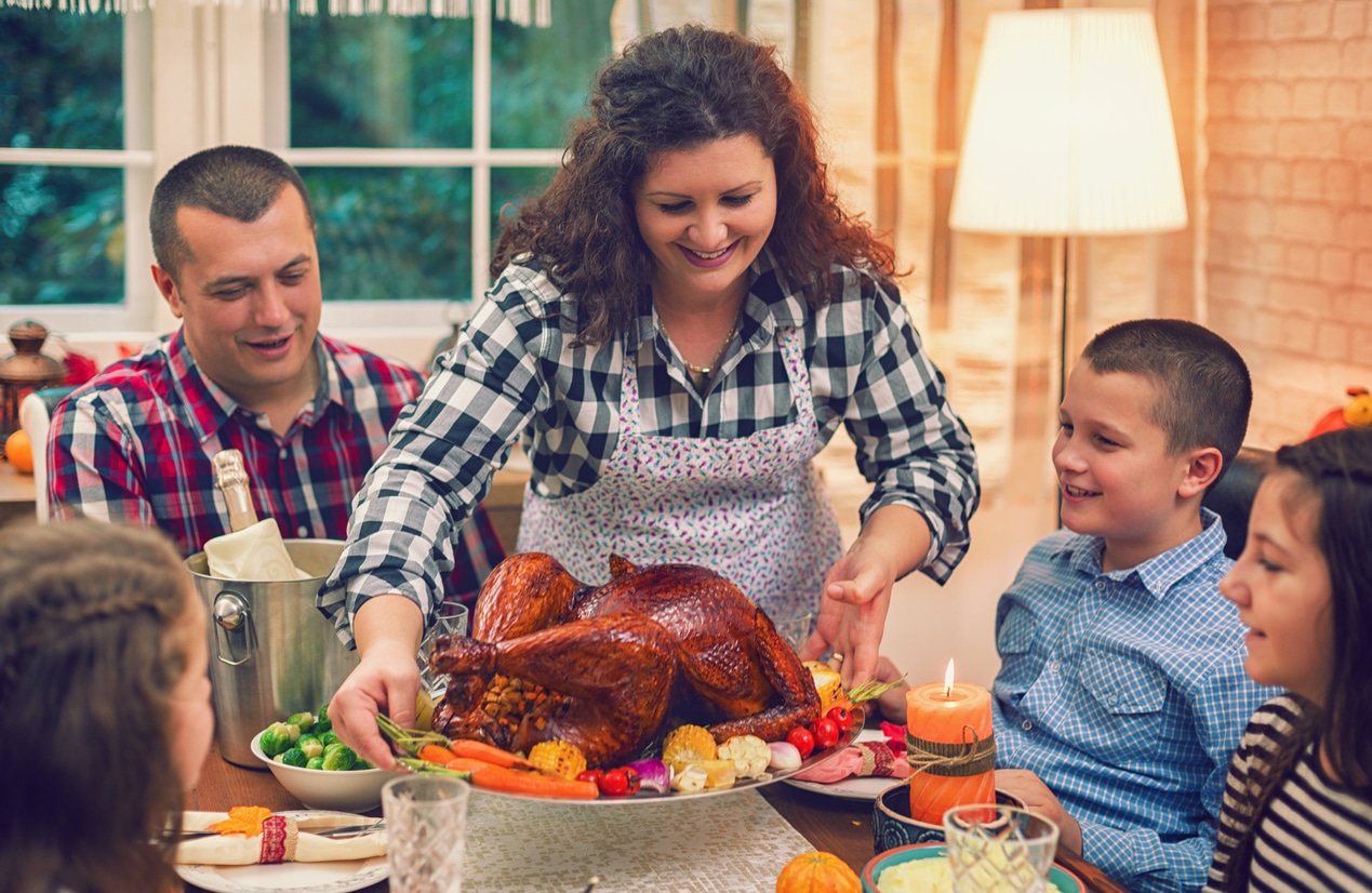 Mom bringing a roast turkey to the dinner table.