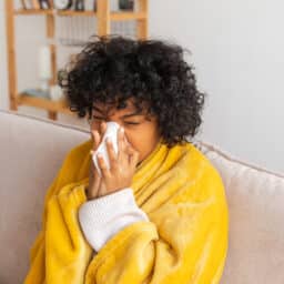 Young woman blowing her nose at home