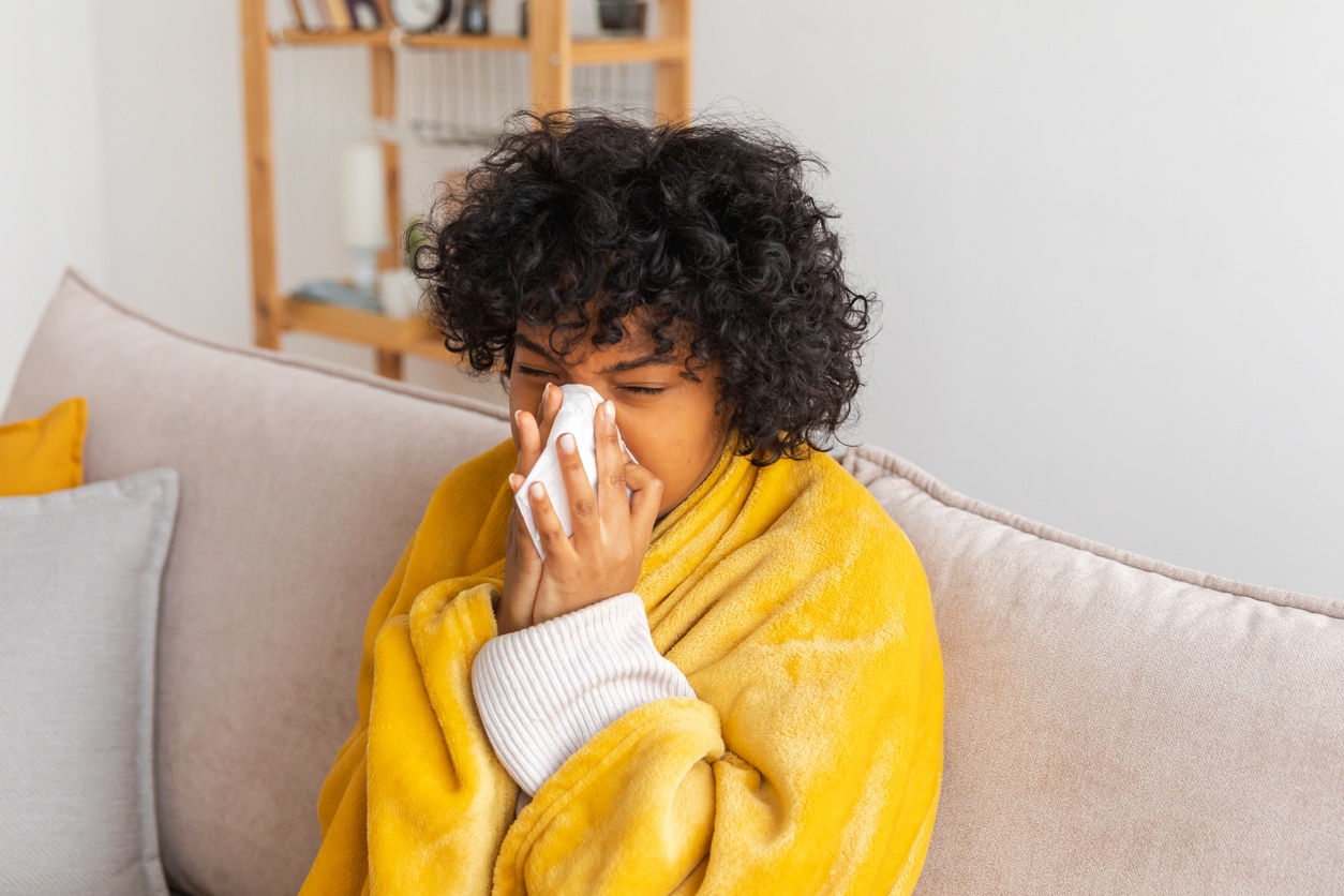 Young woman blowing her nose at home.