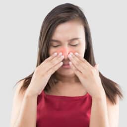 Woman holding her red sinuses